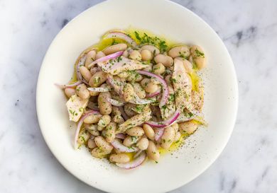 White bean, tuna, and pickled red onion salad on a white plate