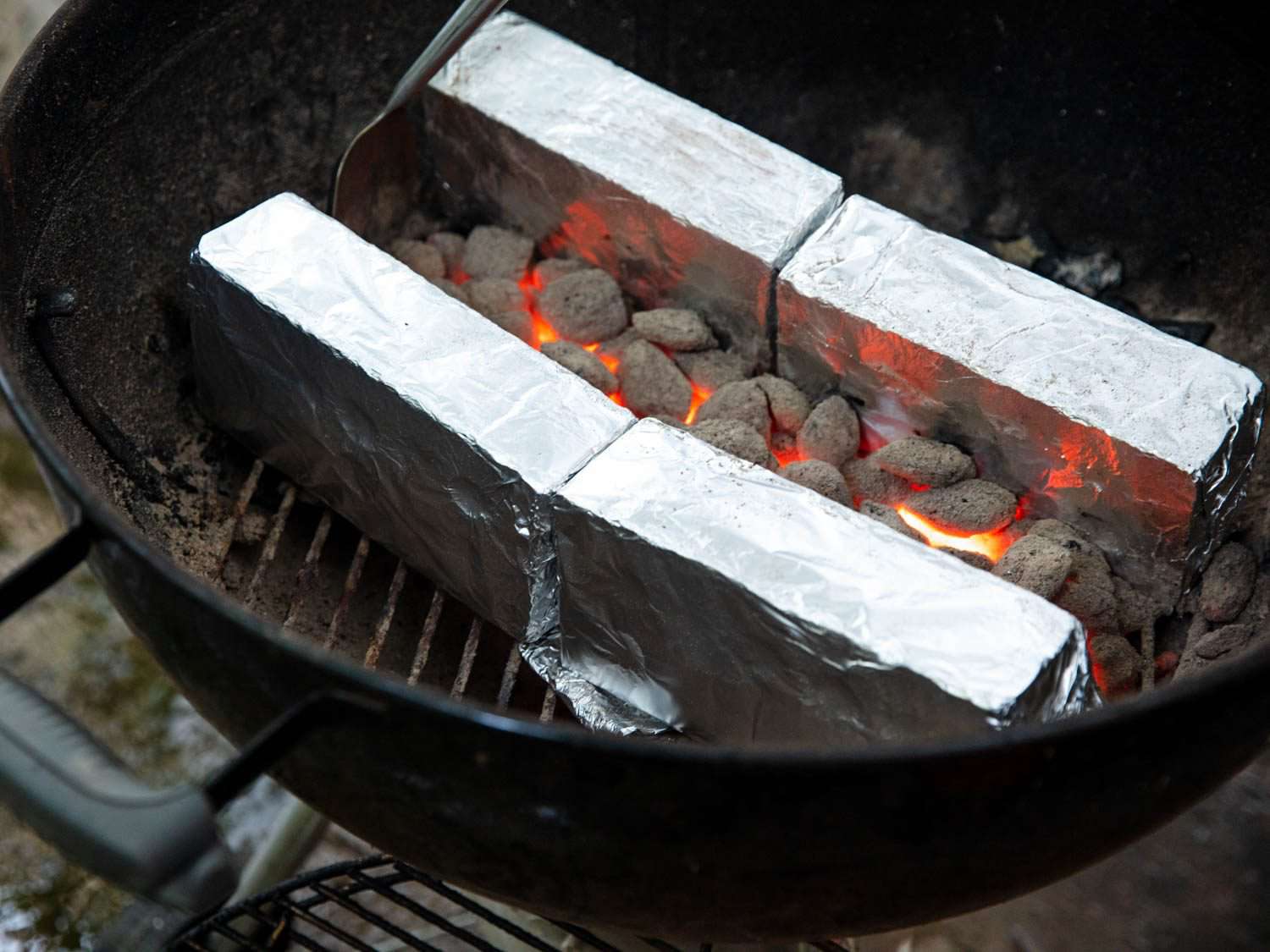 在两个平行的用锡箔包裹的砖砌成的墙之间放置燃烧着的煤，用来在水壶烤架上烤串