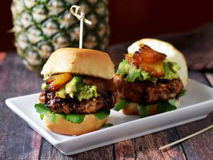Two mini salmon burgers with pineapple and avocado.
