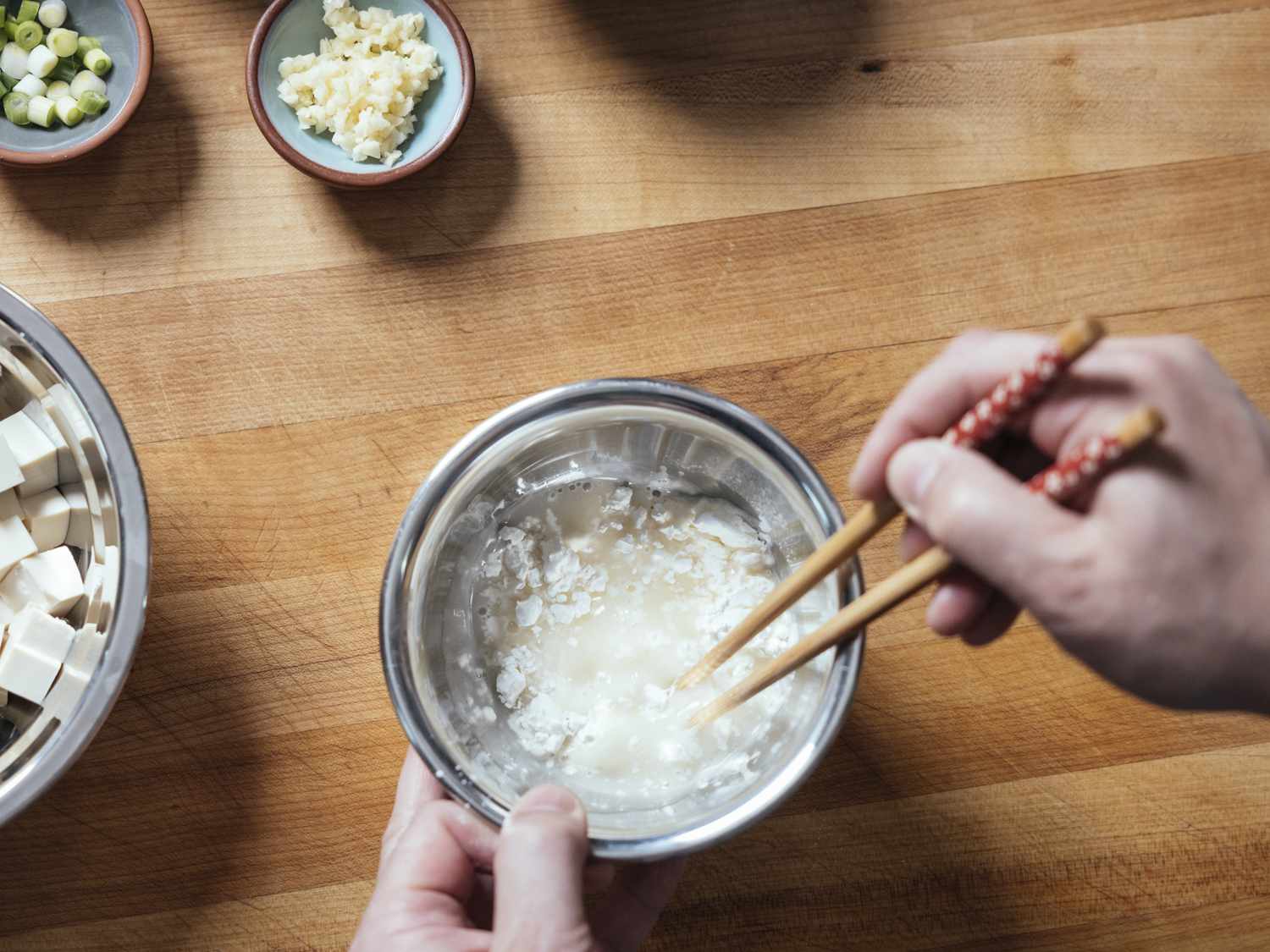 用筷子将玉米淀粉浆混合在金属碗中。