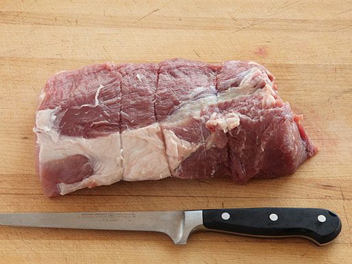 生的西冷肉放在木砧板上，旁边放着一把切肉刀。