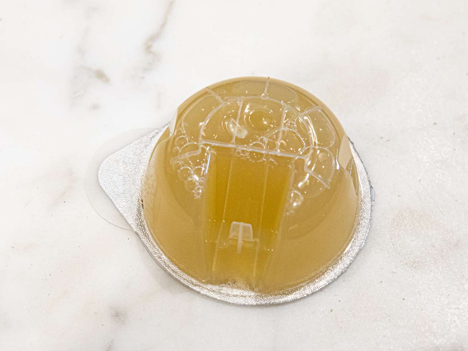 A closeup look at a Bartesian cocktail pod that's sitting on a marble surface