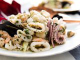 Italian seafood salad with calamari, scallops, shrimp, and mussels on a white plate.
