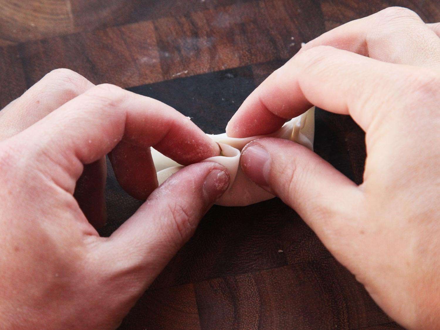 用双手在饺子皮上折褶，做成饺子饺。