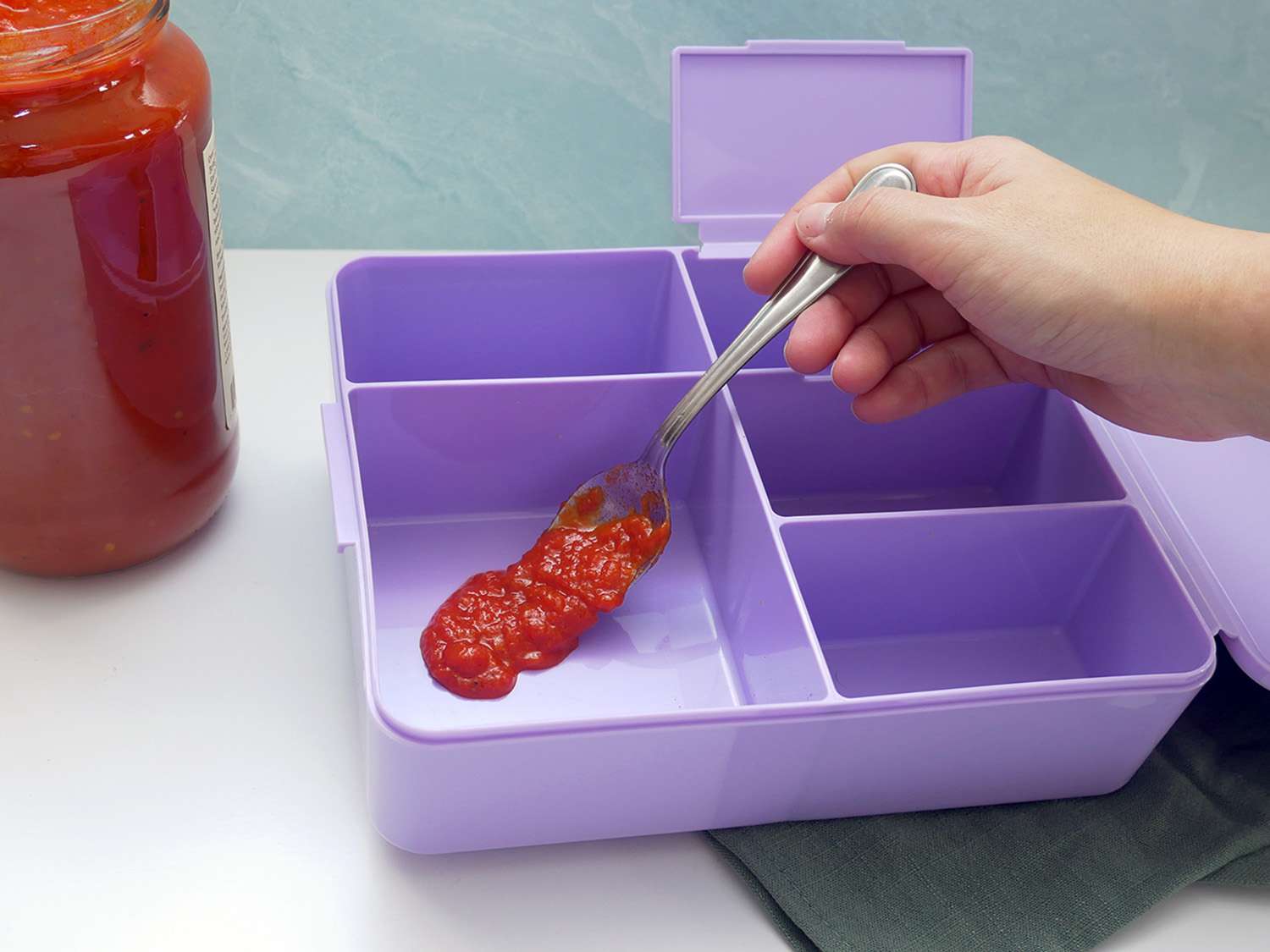 将一勺番茄酱放入陶器谷仓便当盒中进行染色测试。