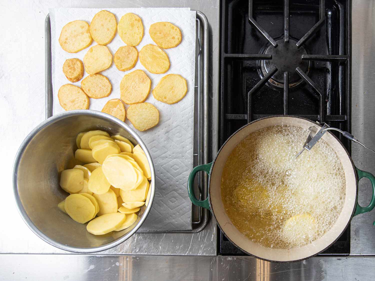 俯拍土豆在荷兰烤箱里炸，一碗土豆片和放在纸巾上的土豆。