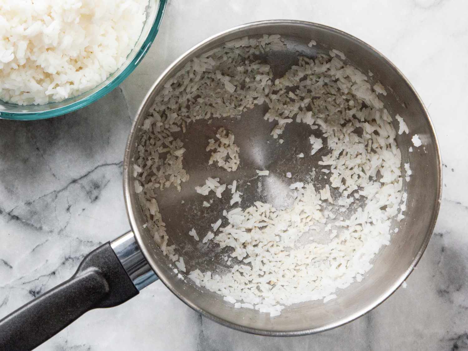 rice stuck in the bottom of a saucepan beside a bowl of cooked rice