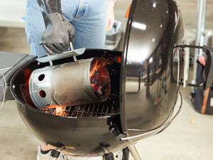 一个人使用一个烟囱起动器热煤倒入charcaol烧烤