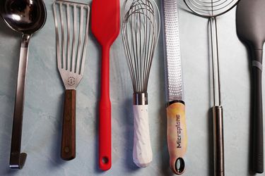 a variety of kitchen tools and utensils on a blue surface