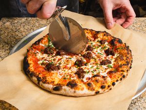 Armenian pizza being cut with a pizza cutter
