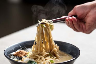用筷子从一碗拉面中拔出面条