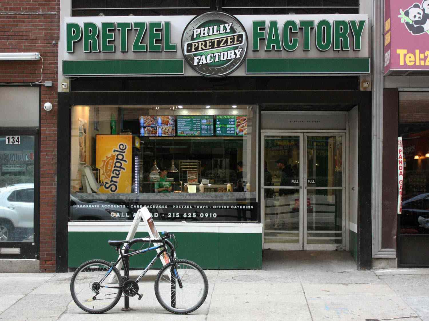 费城椒盐脆饼工厂的外部，这是一家特许经营的费城椒盐脆饼连锁店的一部分，前面停着一辆自行车