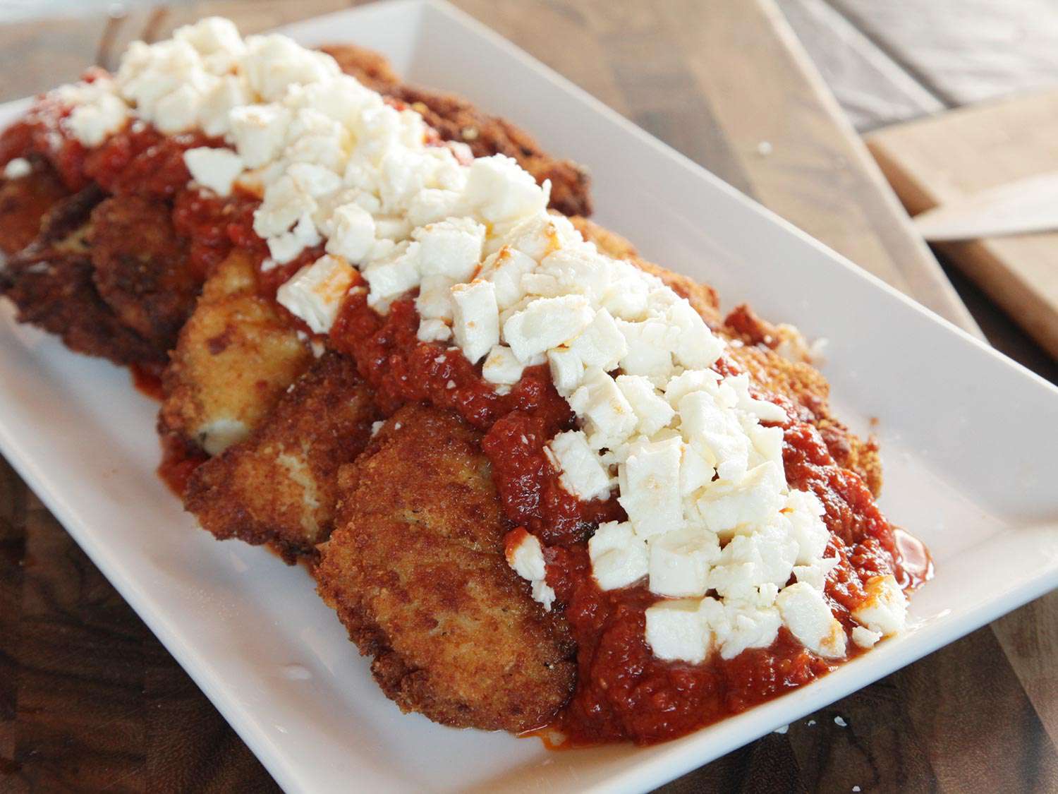 Mozzarella and parmesan cheeses layered over red sauce down the center of shingled fried chicken breasts