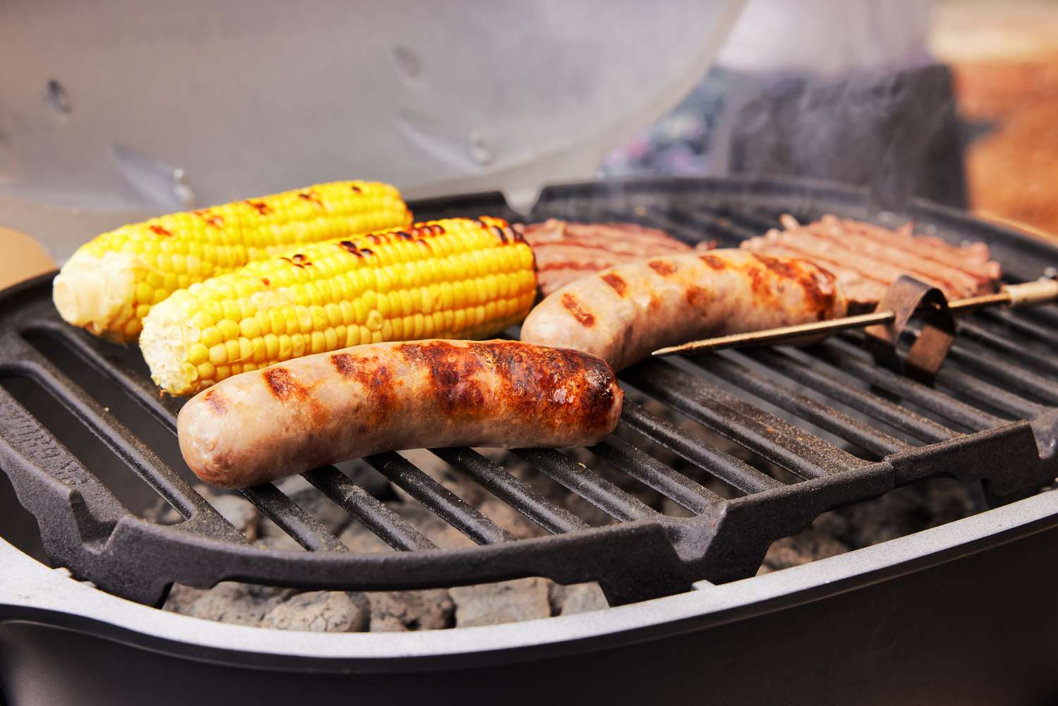 一个特写镜头看香肠和玉米在便携式木炭烤架烧烤