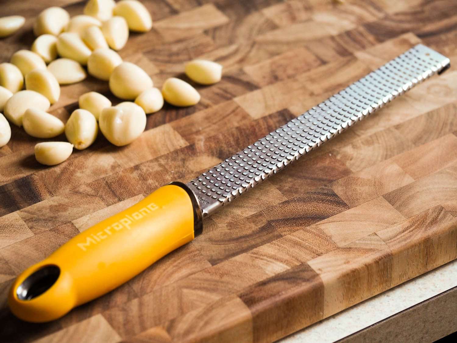 切菜板上的微型刨刀放在整颗大蒜旁边。