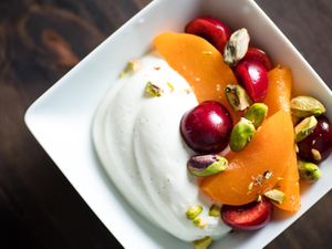 头顶上的一碗夏天水果和生希腊酸奶点缀以开心果。
