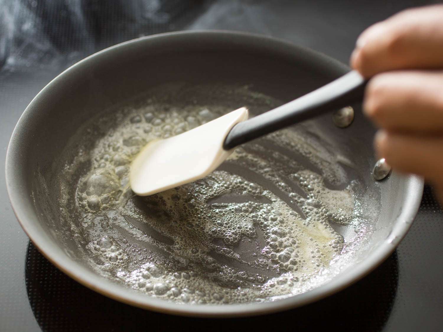用硅铲在不粘锅中搅拌融化的黄油。