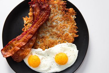 Crispy shredded hash browns with sunny-side up eggs and bacon