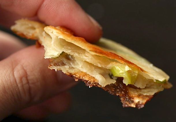 一只手拿着一片葱薄煎饼，呈五层状。