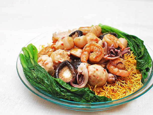 煎蛋面配海鲜(鱿鱼、虾、扇贝和鱼丸)和蘑菇配蔬菜，盛在盘子里。