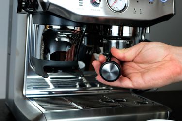 a hand inserts a portafilter into an espresso machine