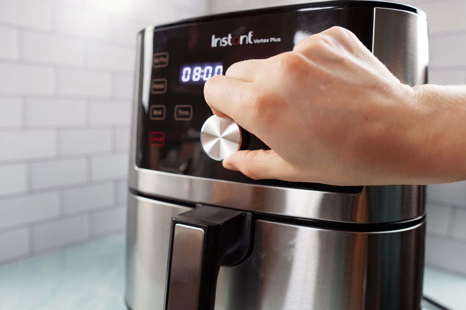 一只手使用空气炸锅的控制旋钮改变烹饪时间