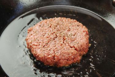由Beyond burger制作的调味汉堡肉饼，在铸铁煎锅中煎炸。