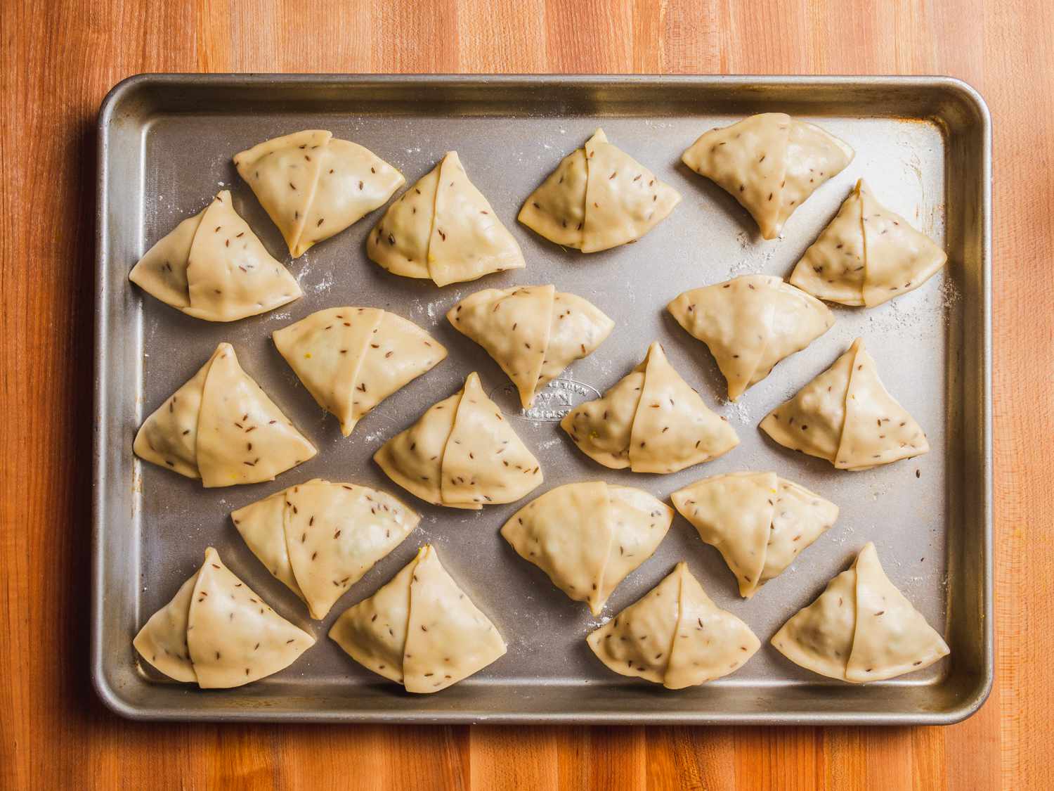 Wrapped samosas on a lightly floured baking sheet, ready for frying