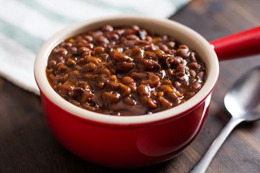 Red single-serving crock with slow-cooked baked beans.
