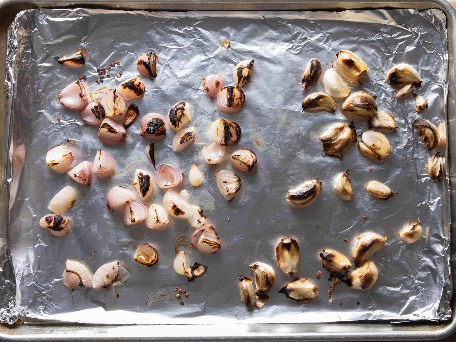 将葱头和未去皮的蒜瓣放在锡箔衬里的烤盘上，烤至有斑点。