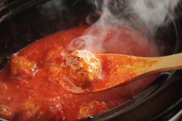 用木勺从番茄酱中捞出炖肉