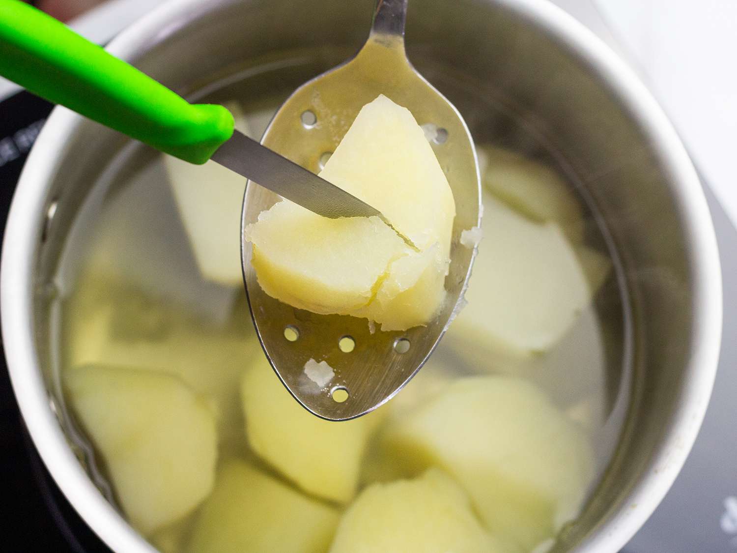 用削皮刀把煮熟的土豆切成薄片放在一锅水里