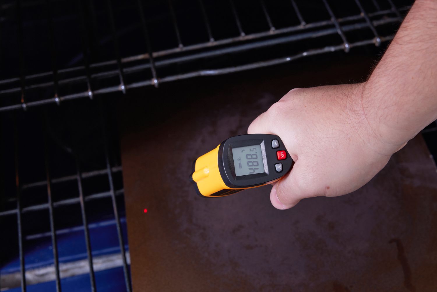 一只手使用红外线温度计烤箱里烤钢的温度