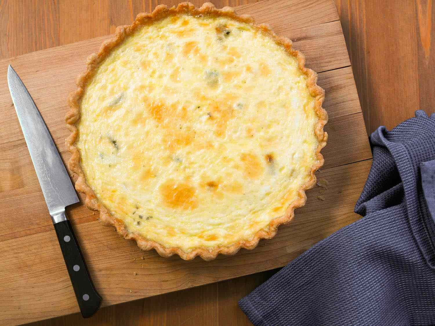 奶酪乳蛋饼放在木砧板上，用刀和厨房毛巾。