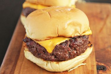 Homemade bison cheeseburgers on a wooden cutting board