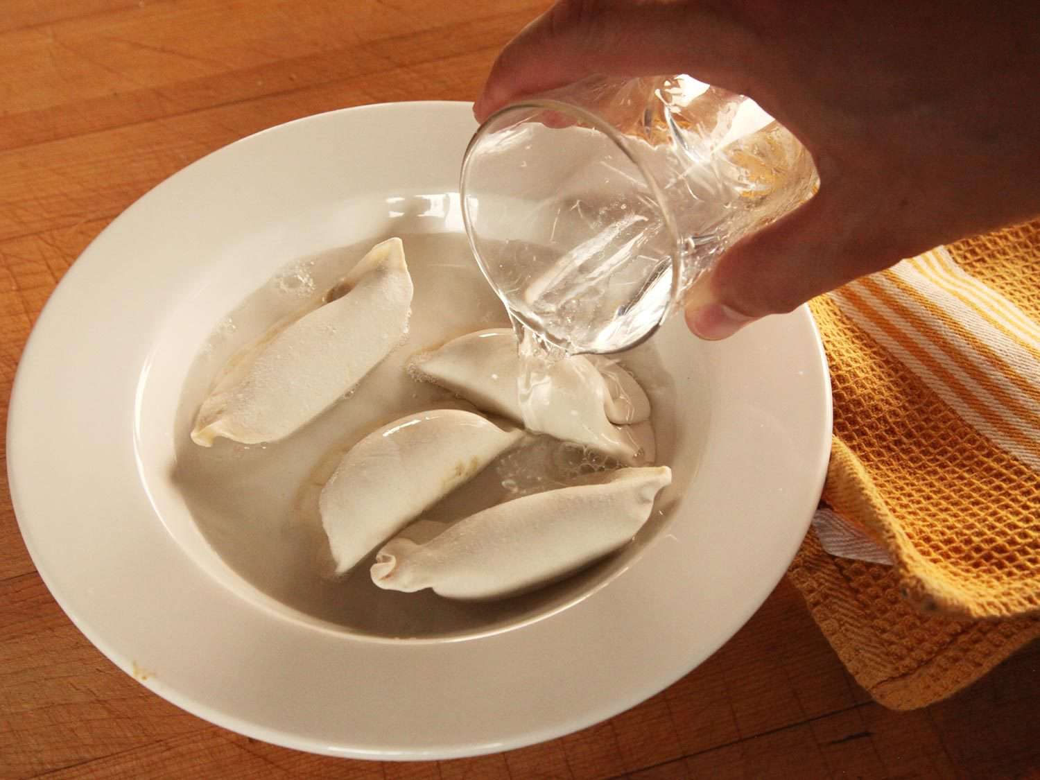 把水倒进一碗冻饺子里。