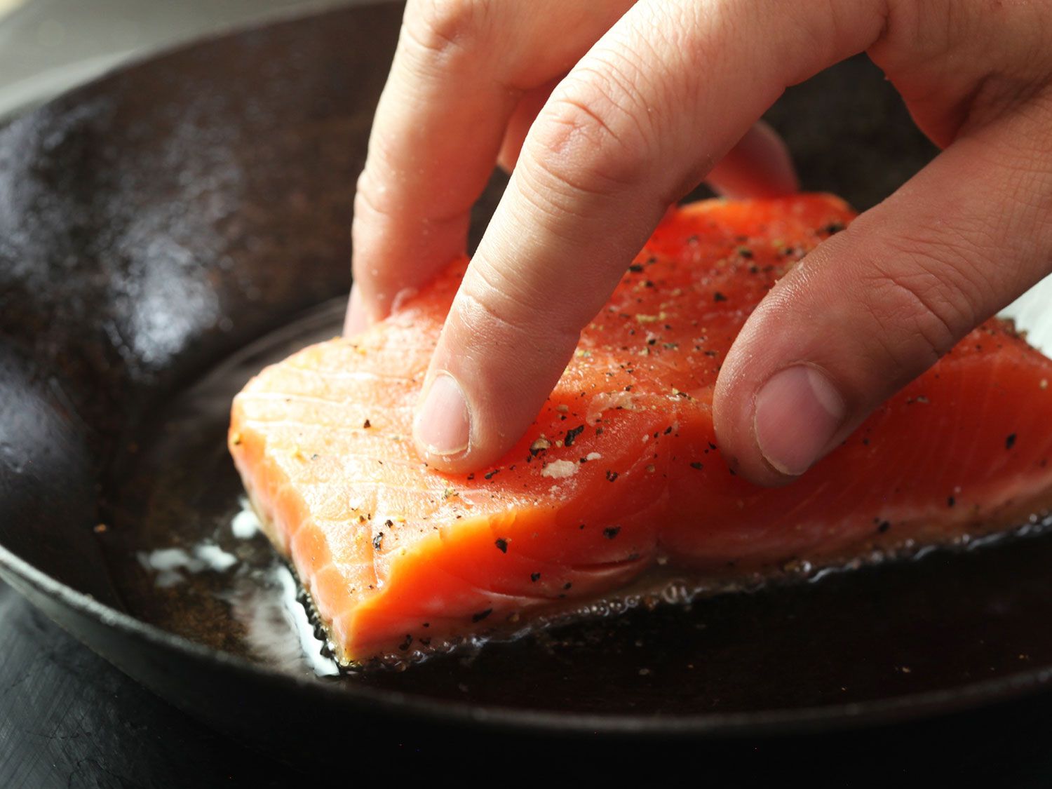 将带皮的三文鱼片放入热油煎锅中，鱼皮朝下。