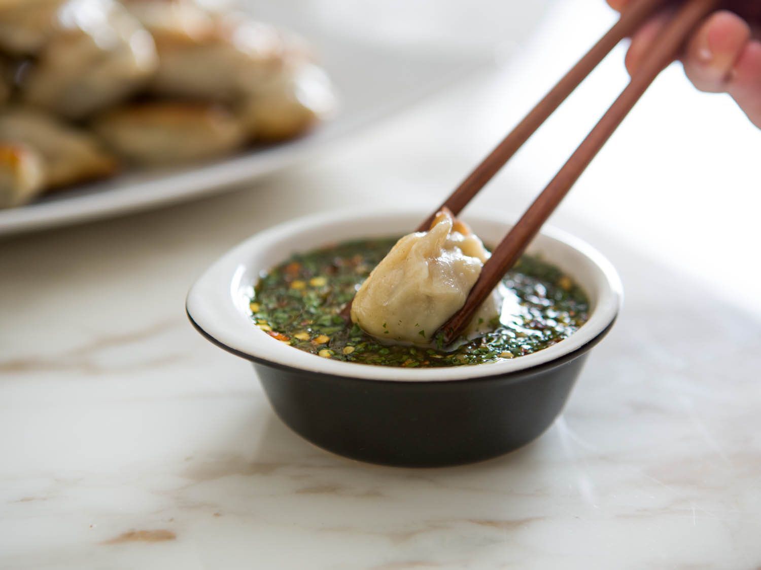 用筷子将饺子蘸上鱼露。
