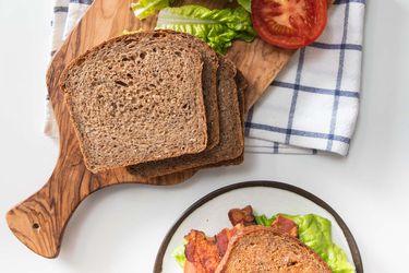 Overhead shot of sliced multigrain bread, tomato slice, and lettuce for BLT