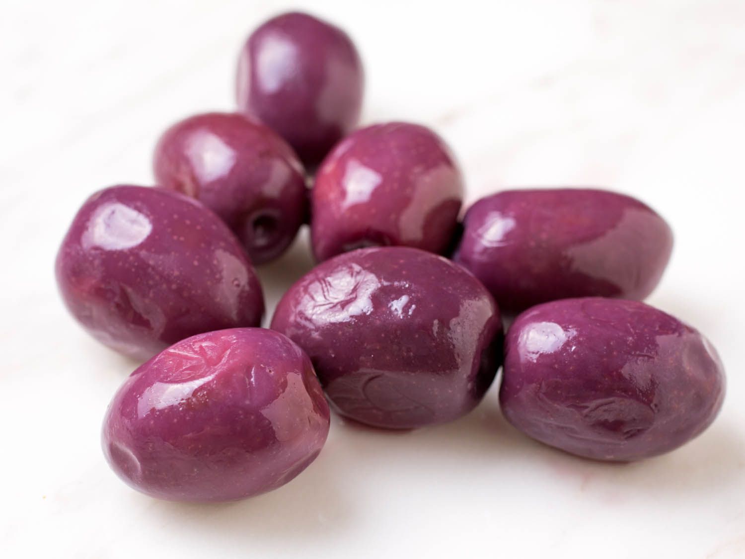 微皱的特写，明亮的紫色橄榄在大理石表面
