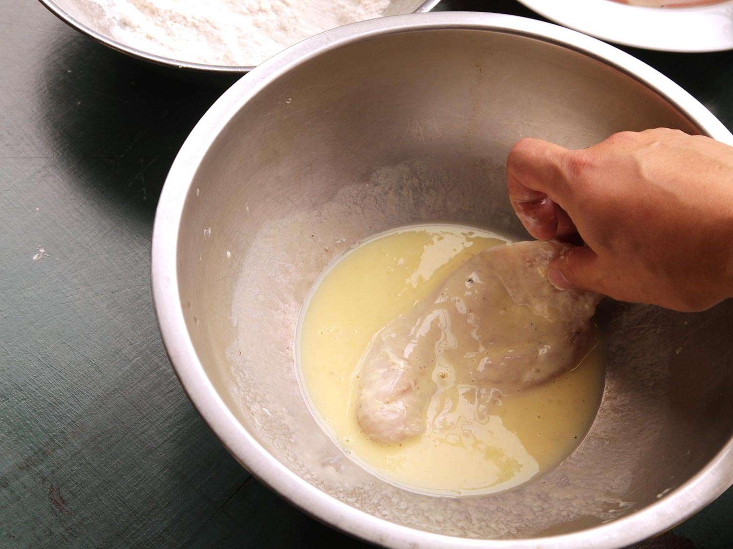 Dipping flour-coated chicken breast in beaten egg