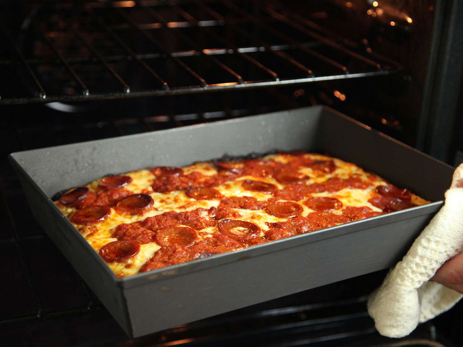 用毛巾挡住手，把烤好的底特律披萨从烤箱里拿出来gydF4y2Ba