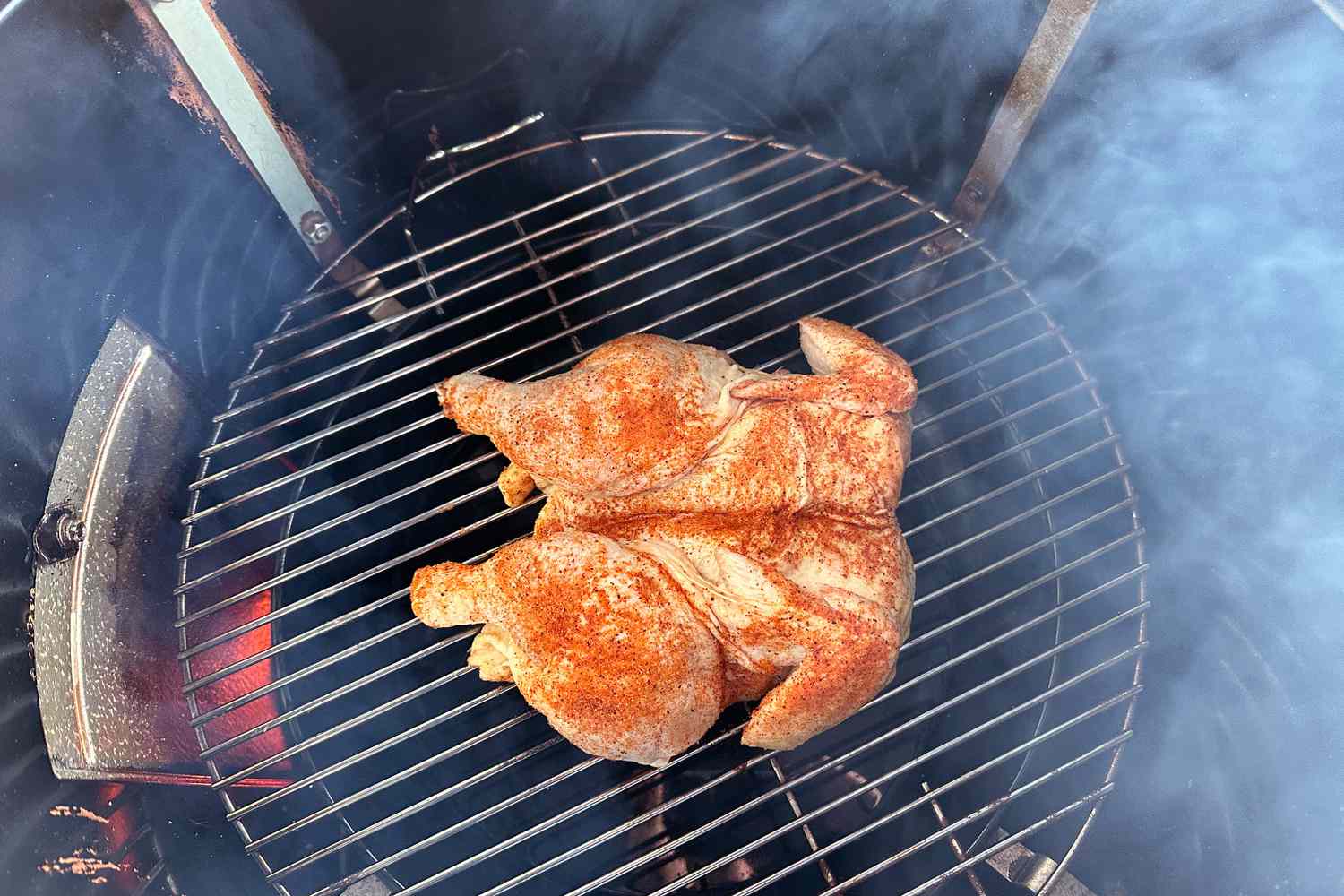 a closeup look at a spatchcocked chicken cooking on a charcoal grill