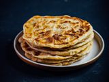 A stack of aloo paratha with spiced potato filling on a plate.