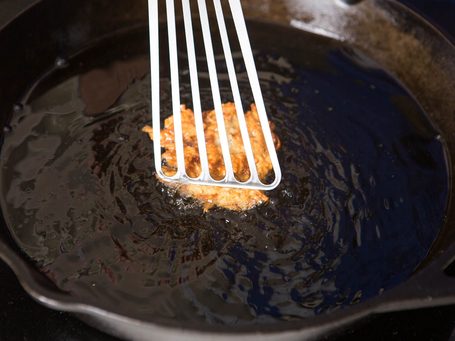 在铸铁锅里，用一个有弹性的金属刮刀压下煎饼gydF4y2Ba
