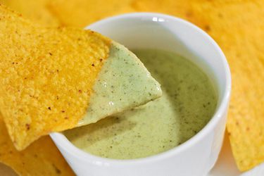 Tortilla chip dipped in salsa verde