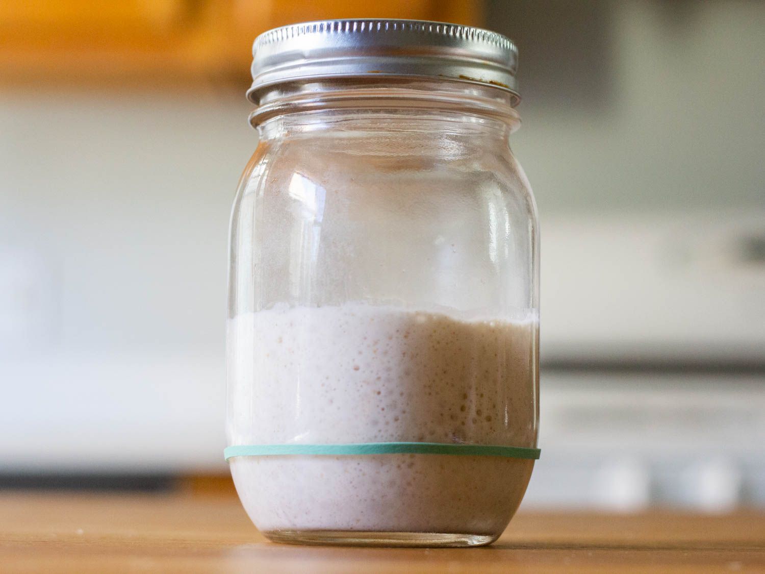 用于制作酸面包的酵母在玻璃罐中上升，大约是初始体积的三倍