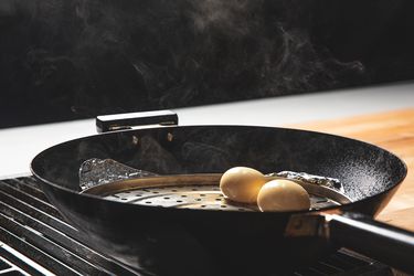 Two eggs being smoked in a wok