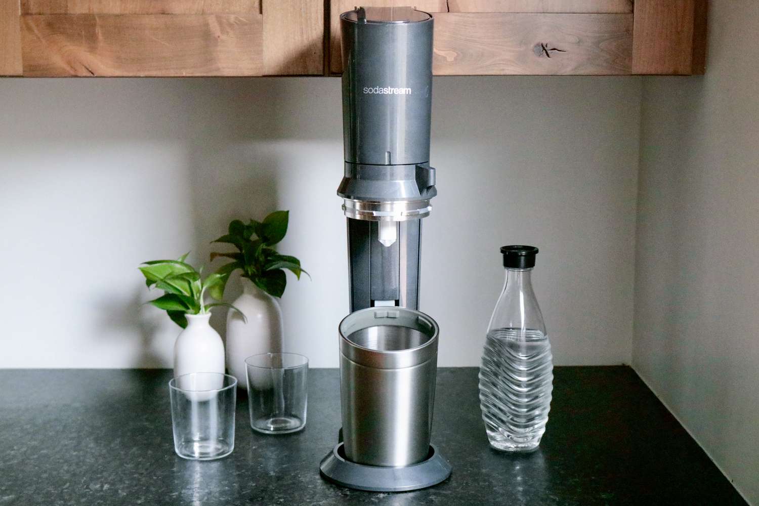 一个SodaStream Aqua Fizz放在厨房的工作台上，旁边是瓶子