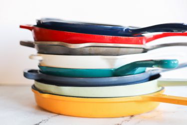 a stack of enameled cast iron skillets in multiple colors